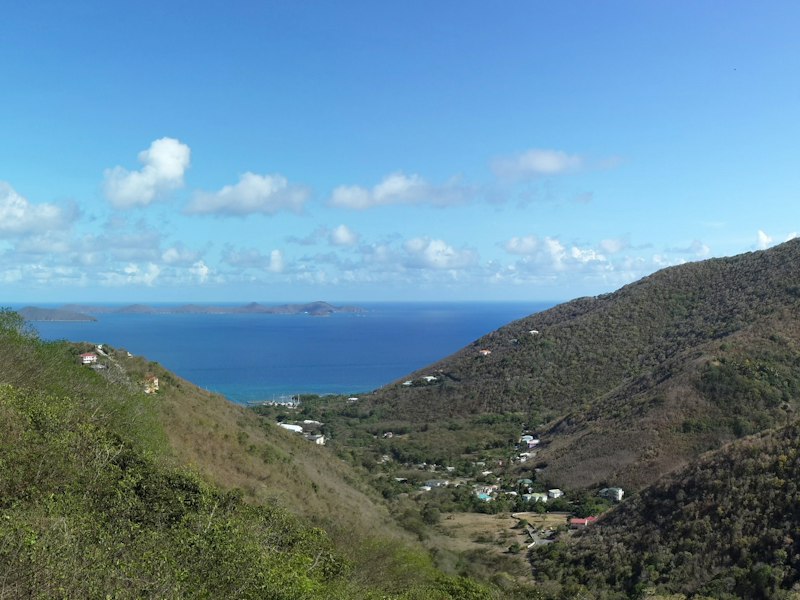 Green hills of Pleasant Valley on Tortola, British Virgin Islands, sloping down to a blue bay with islands on the horizon