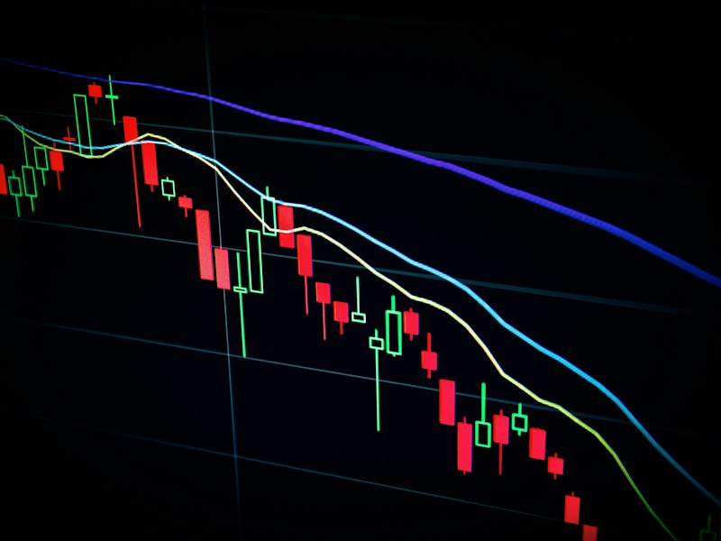 Stock market candlestick chart with red and green bars on a dark screen
