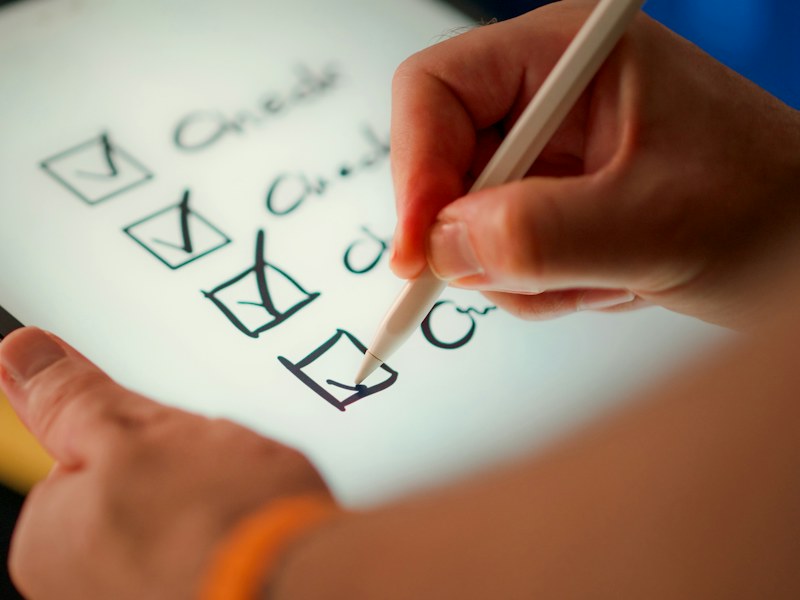 A hand ticking off items on a paper checklist