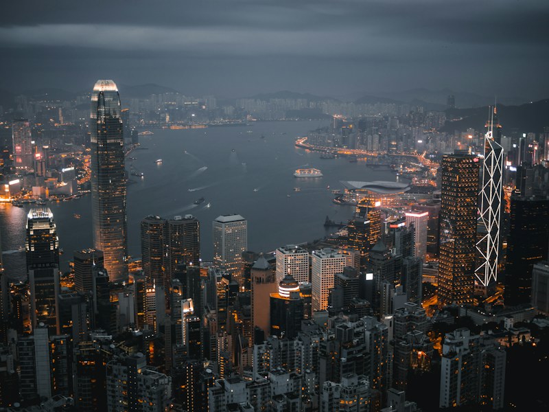 Aerial view of the illuminated Hong Kong skyline and Victoria Harbour at dusk