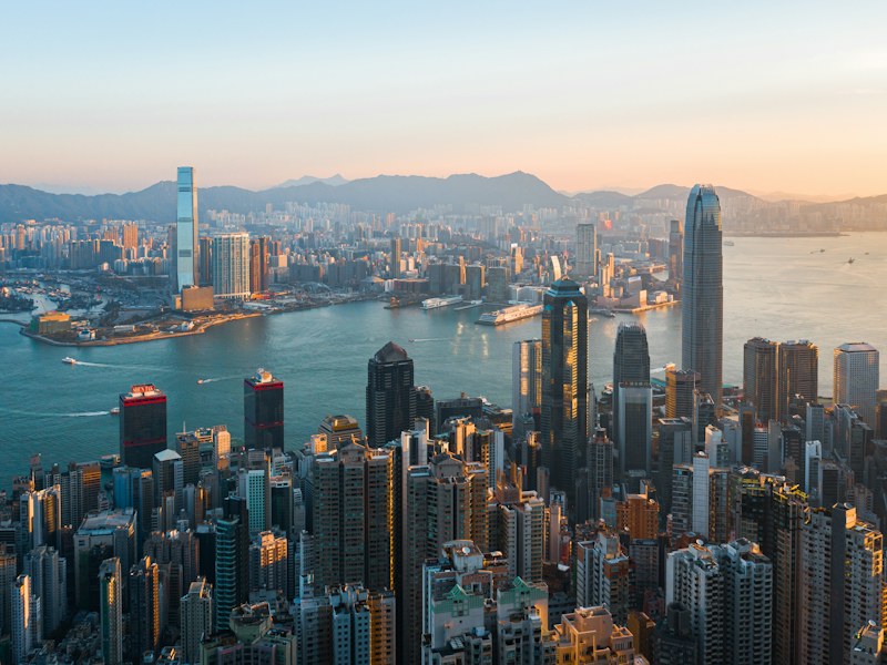 High-angle view of the Hong Kong skyline across Victoria Harbour at golden hour