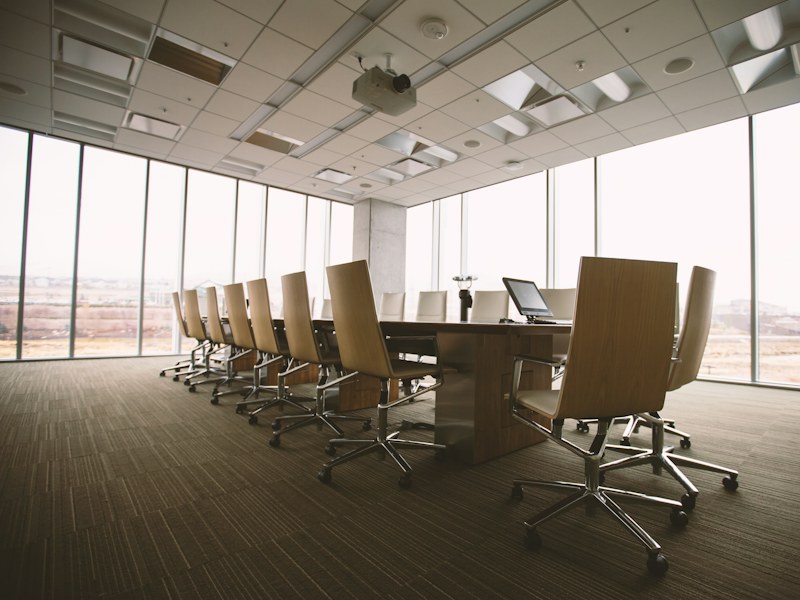 Empty oval wooden conference table with chairs in a boardroom