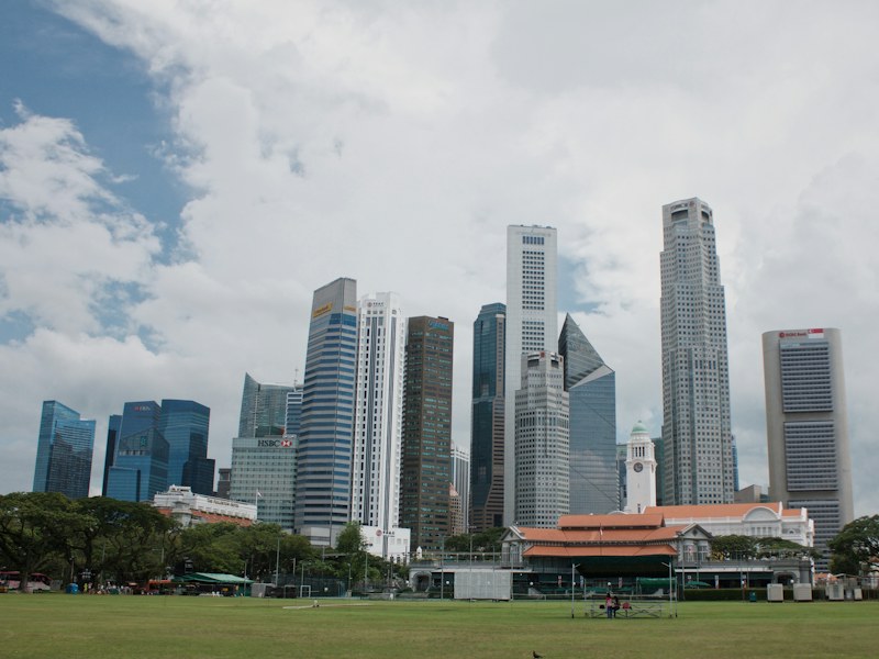 Singapore central business district towers seen across the Padang under a cloudy sky