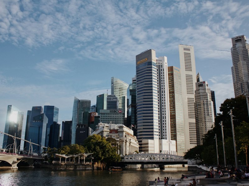 Singapore's Raffles Place office towers seen across the Singapore River, with the Fullerton building and Cavenagh Bridge in the foreground