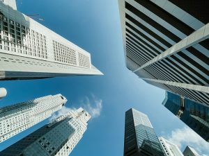 Upward view of glass and concrete office towers against a blue sky in Singapore's central business district