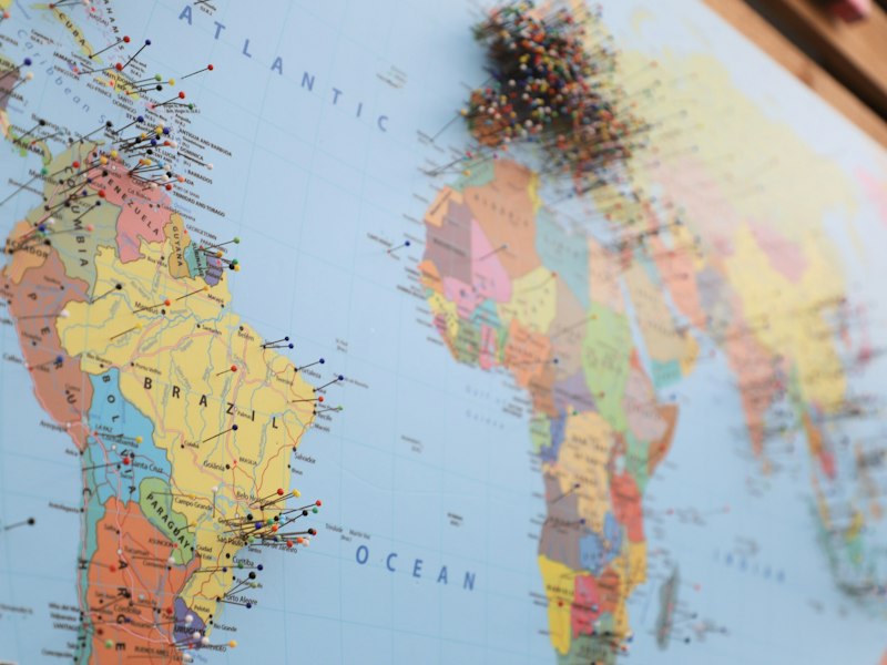 Close-up of a wall map of South America, the Atlantic Ocean and Africa studded with coloured map pins